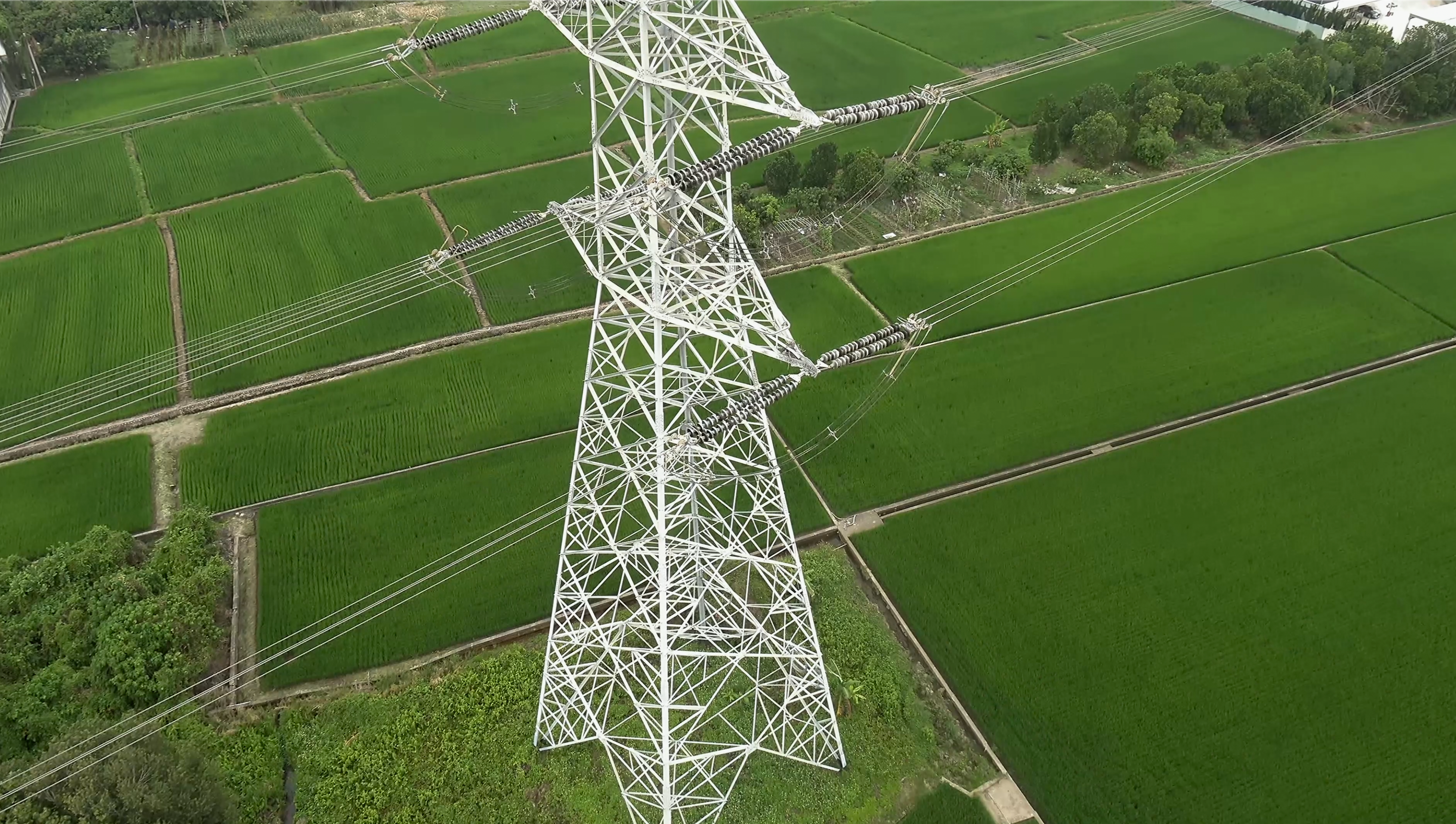 Aerial view of a transmission tower over green fields